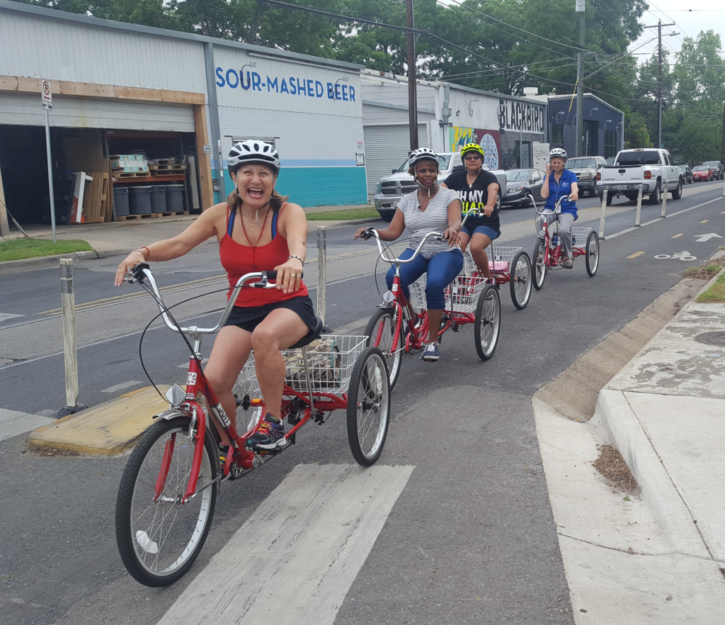 Line of older adults on upright trikes in a cycletrack.